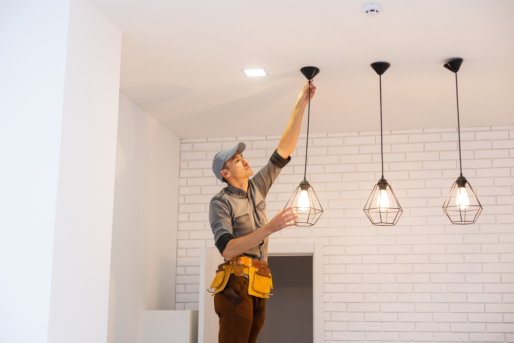 electrician installing light fixtures in a kitchen.